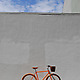 Public Orange D3 Bicycle on sidewalk next to grey wall